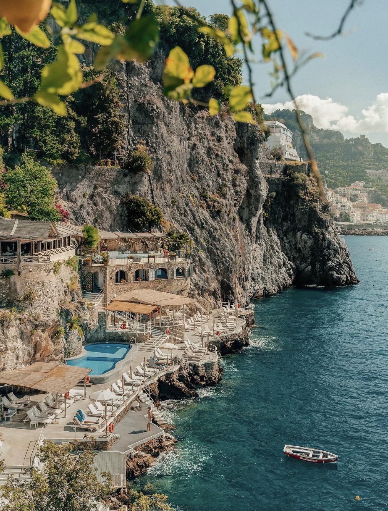 Cliffside pool terrace and swimming platforms on the Amalfi Coast framed by lemon leaves