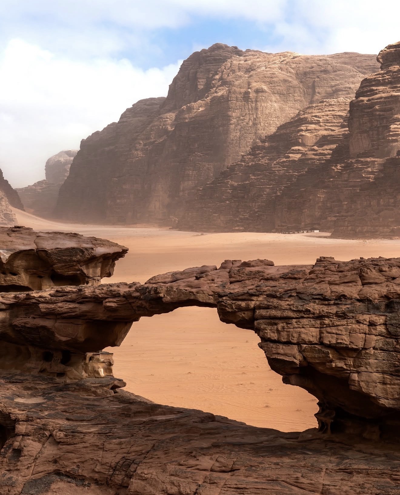 Natural sandstone arch overlooking the monumental cliffs of Wadi Rum