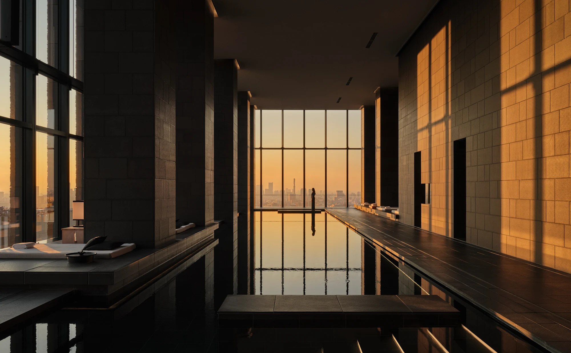 A serene indoor pool overlooking Tokyo in golden evening light