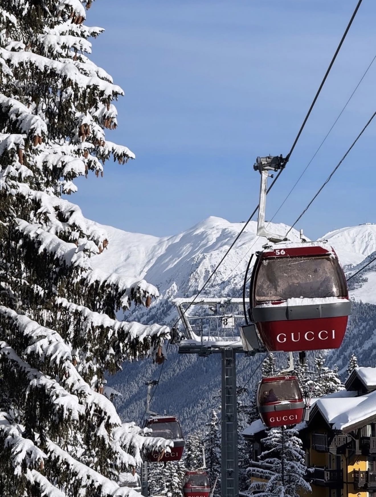 Red gondolas moving above snow-covered chalets in the French Alps