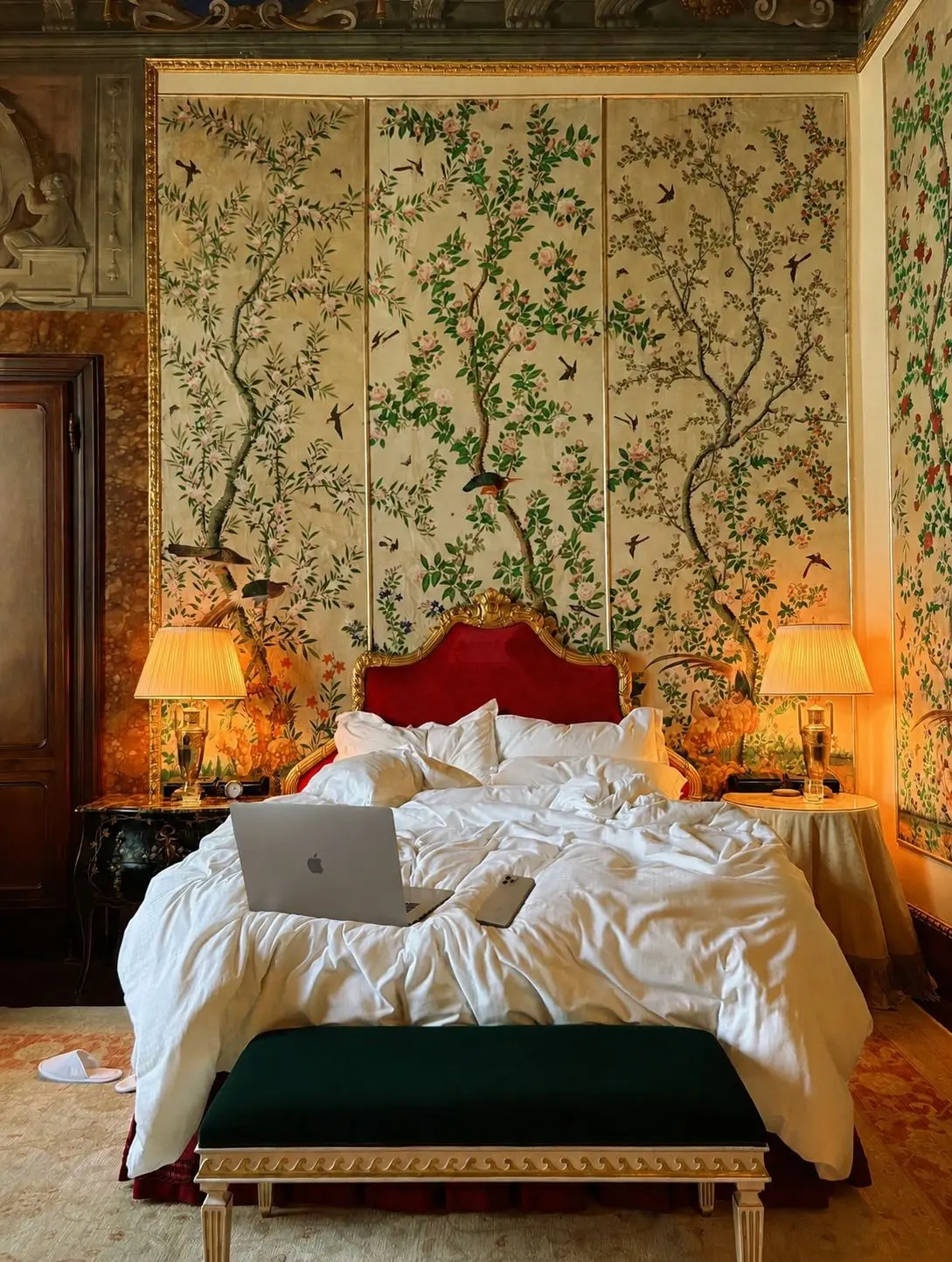 A red velvet headboard and crisp white linens in a hand-painted chinoiserie palazzo bedroom