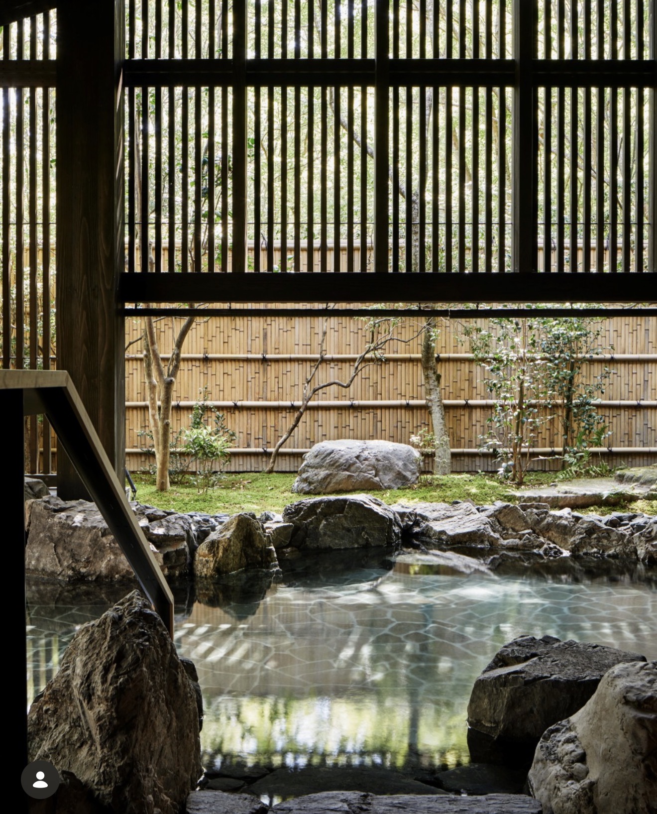 Traditional Japanese open-air bath framed by bamboo and stone
