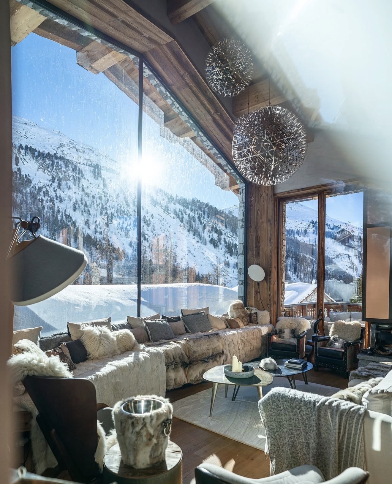 Sunlit chalet living room overlooking snowy mountains