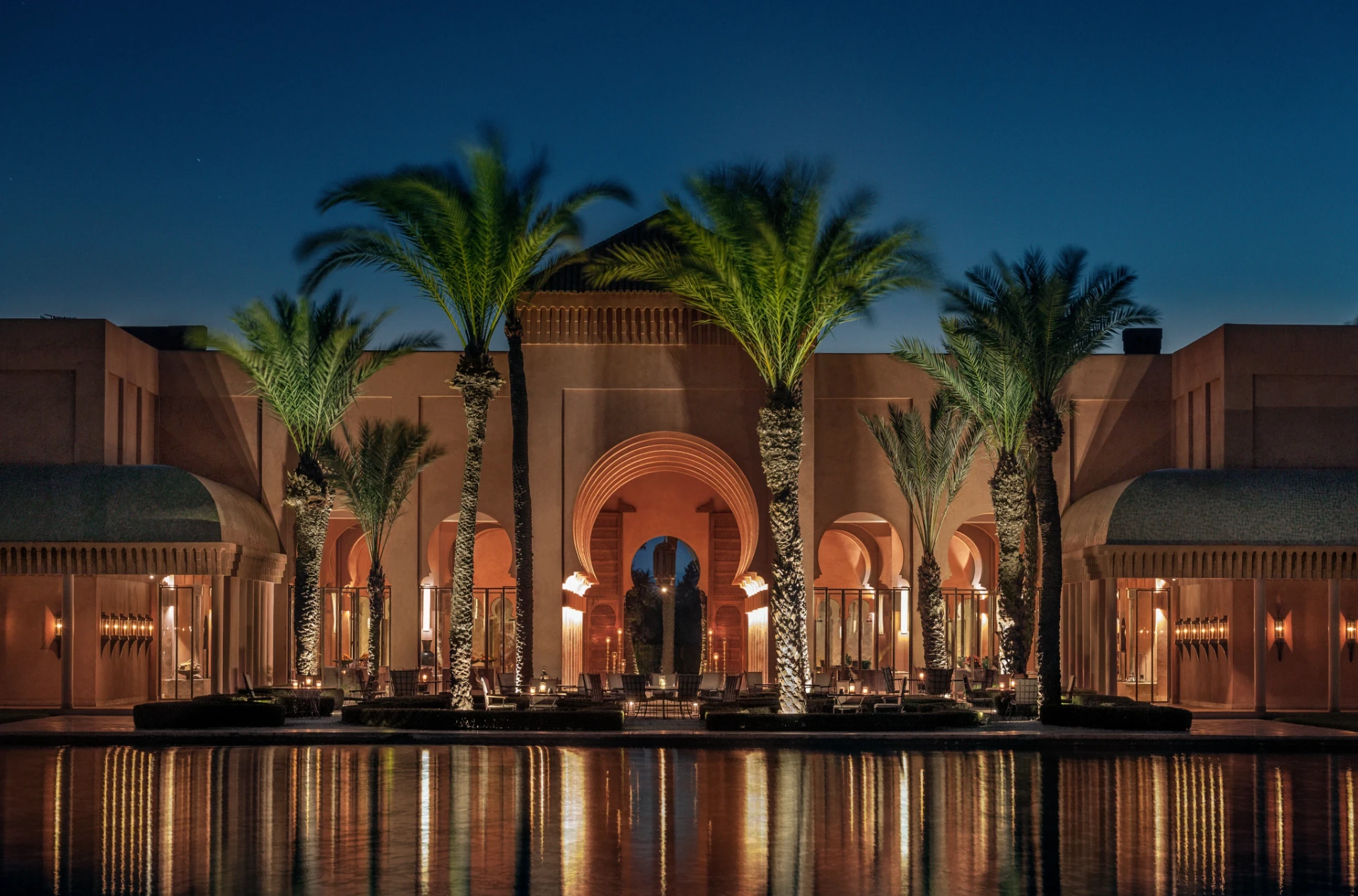 Palm-lined Moroccan pavilion reflected in still water at dusk
