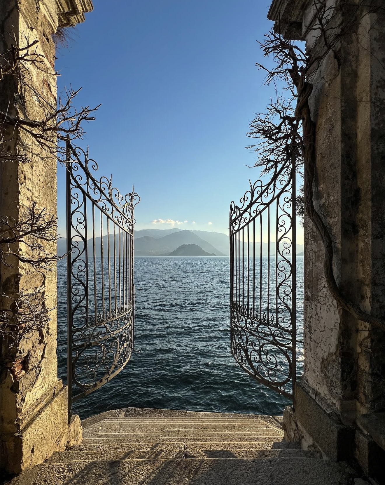 Wrought-iron lakeside gate opening onto the water and mountains at Lake Como