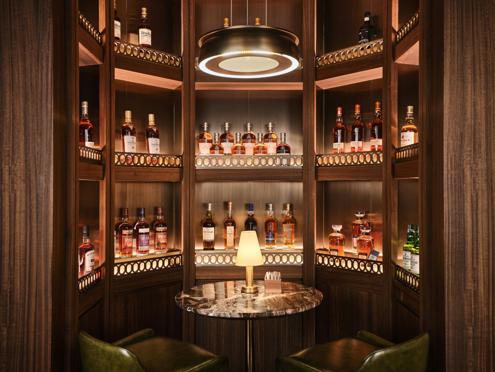 A warmly lit private bar lined with curated whisky bottles and marble detail