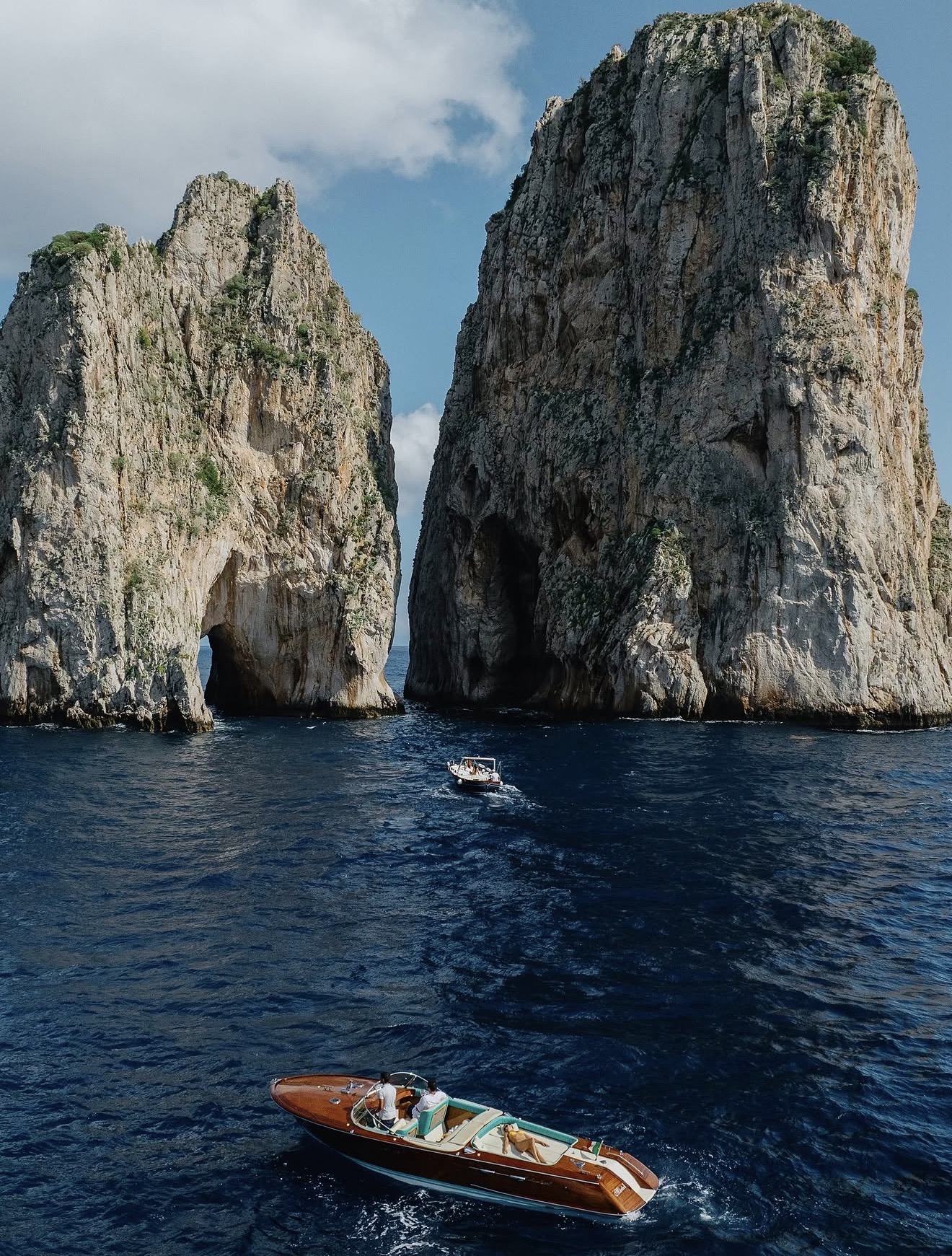 Wooden runabout passing the Faraglioni rocks off Capri
