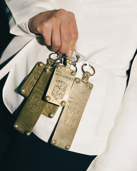 A hotel concierge holding a set of engraved brass room keys