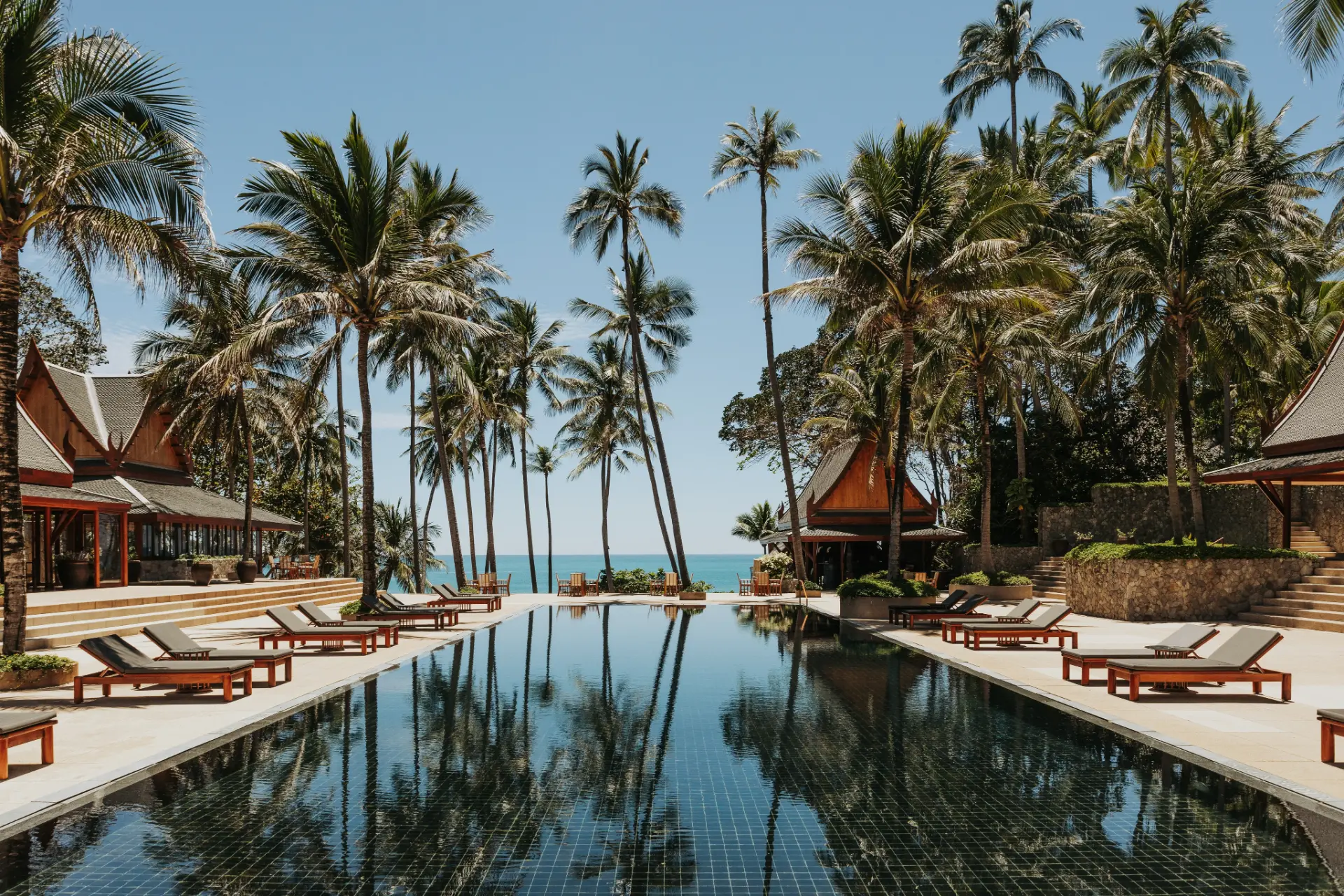 Palm-framed black-tiled pool descending towards the Andaman Sea