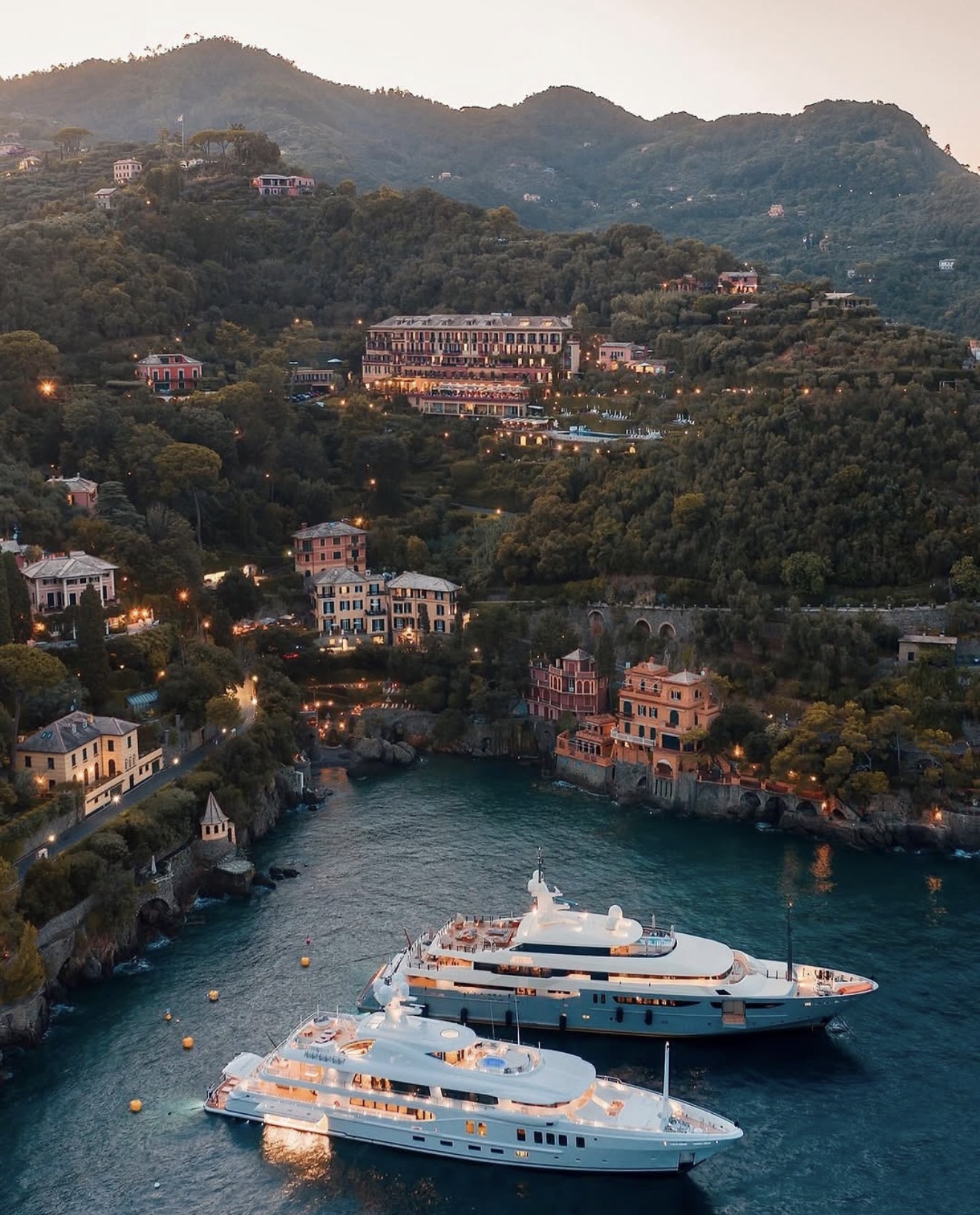 Yachts moored below a hillside hotel in Portofino at dusk