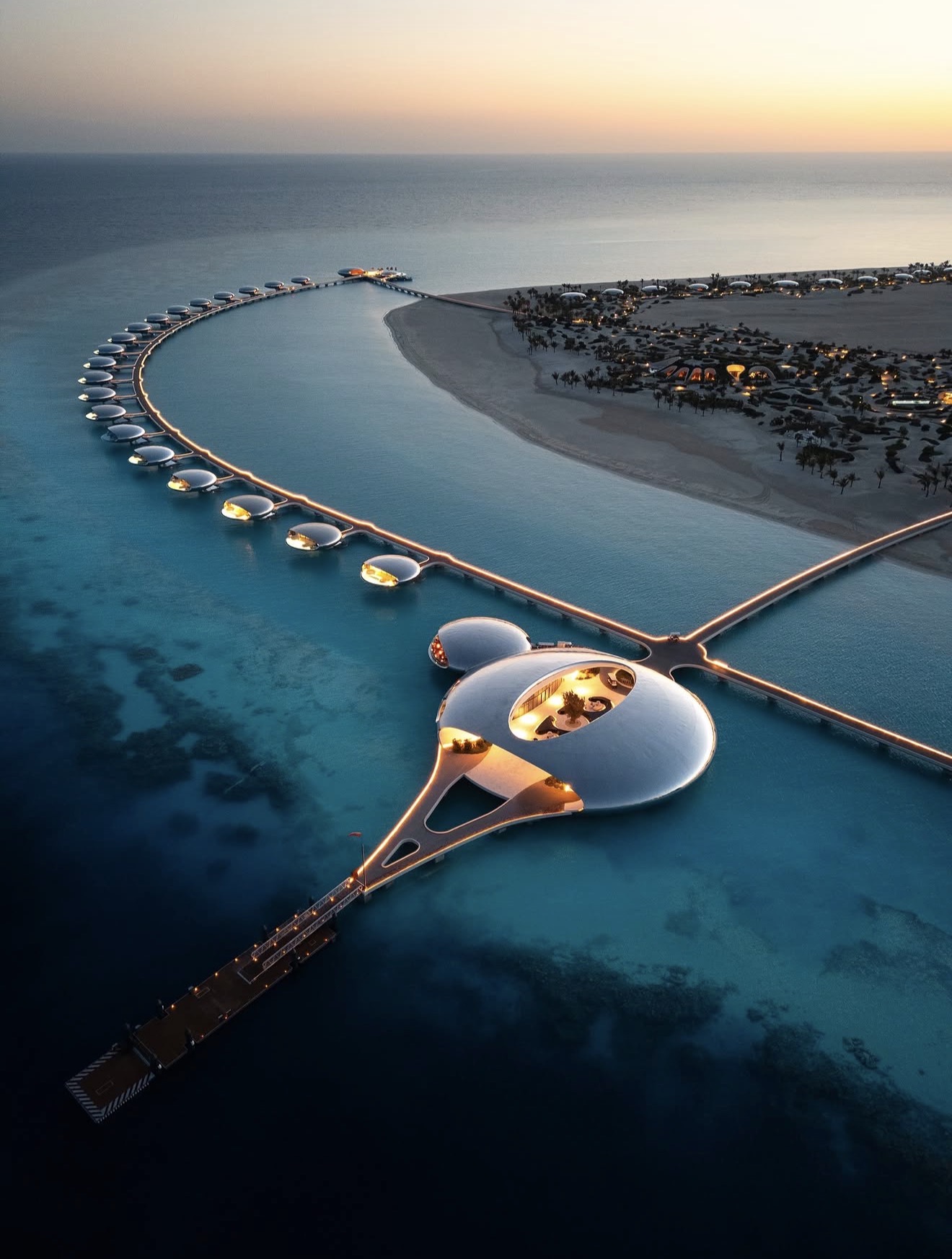 Illuminated overwater villas curving around a Red Sea island at dusk