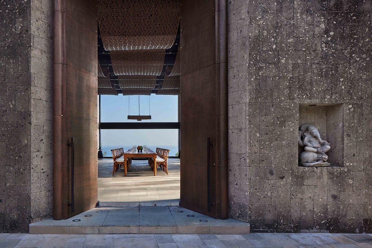 Monumental stone entrance framing a dining terrace and the sea