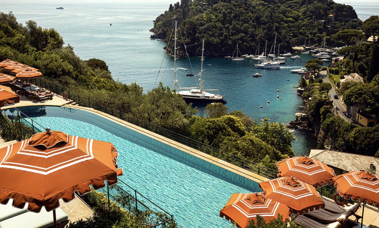 Infinity pool with orange parasols above the bay of Portofino
