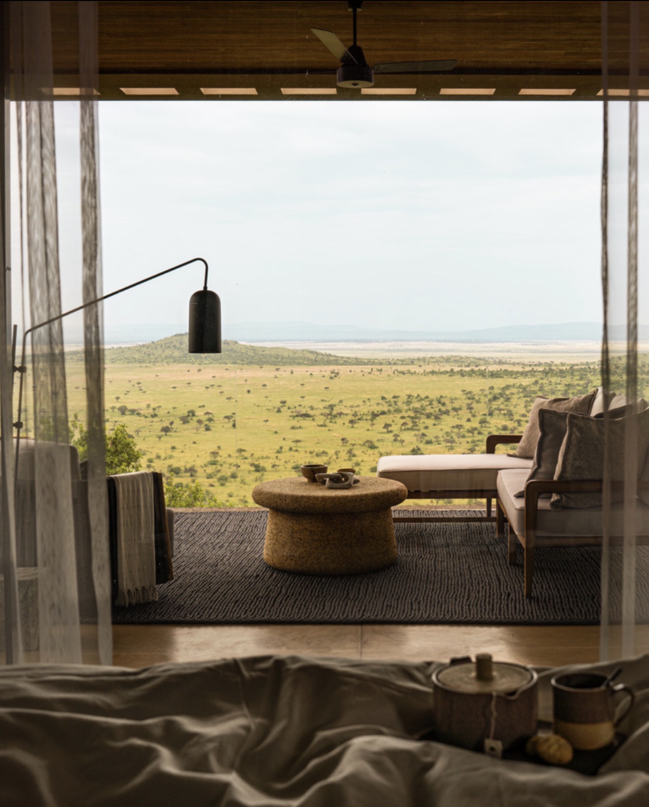 Suite terrace framing the open plains through linen curtains