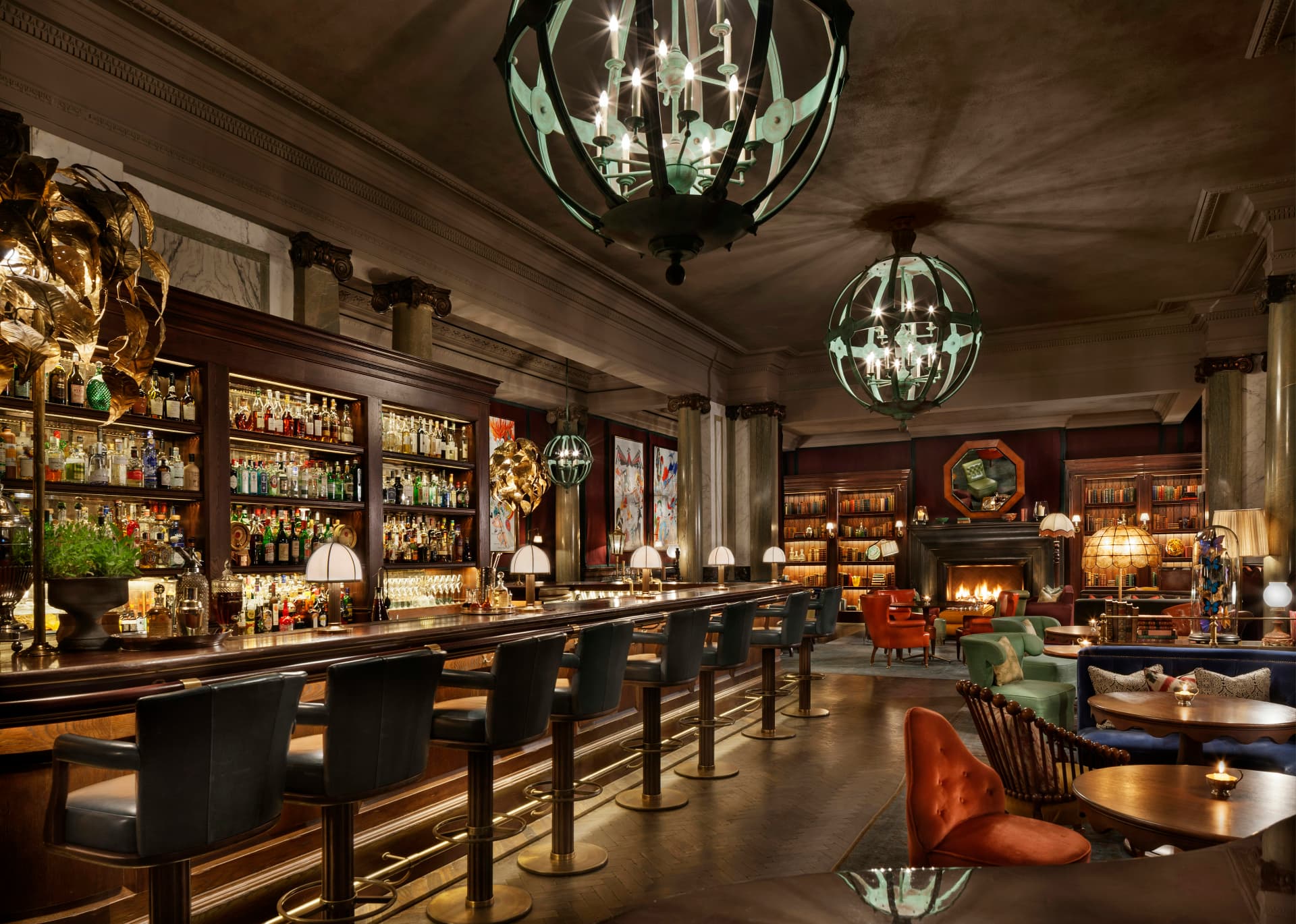 A grand London hotel bar with chandeliers, marble columns and leather stools